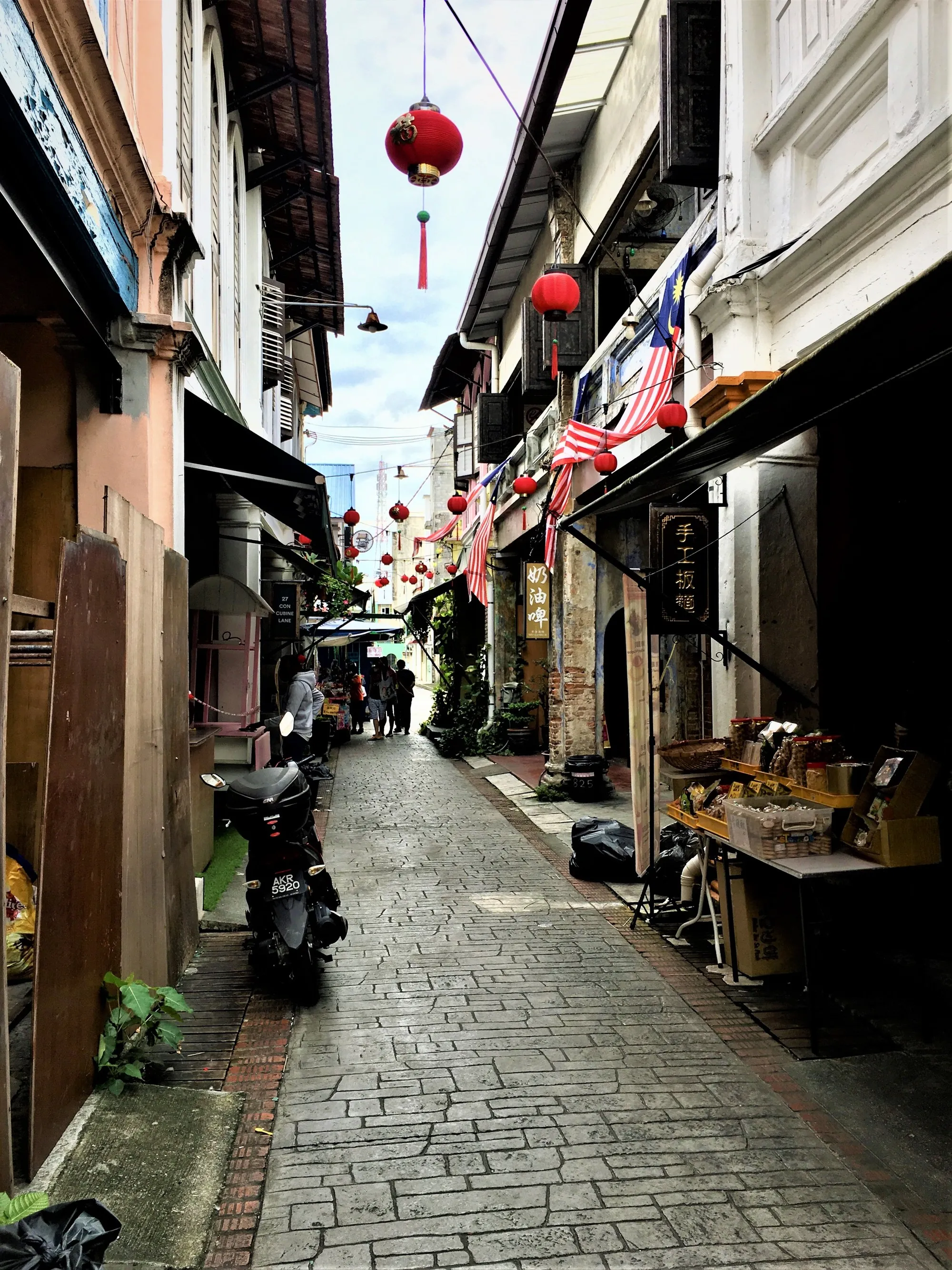 Lorong sempit berturap di antara rumah kedai dua tingkat yang digantung tanglung merah, Lorong Panglima, Ipoh