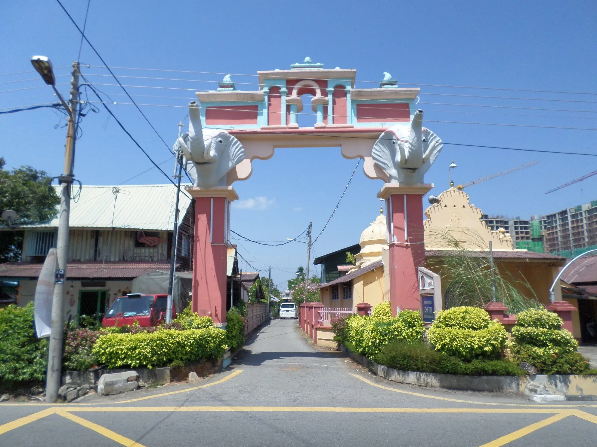 Gerbang berlengkung merah jambu dengan patung gajah di pintu masuk lorong kediaman yang tenang di Kampung Chetti, Melaka