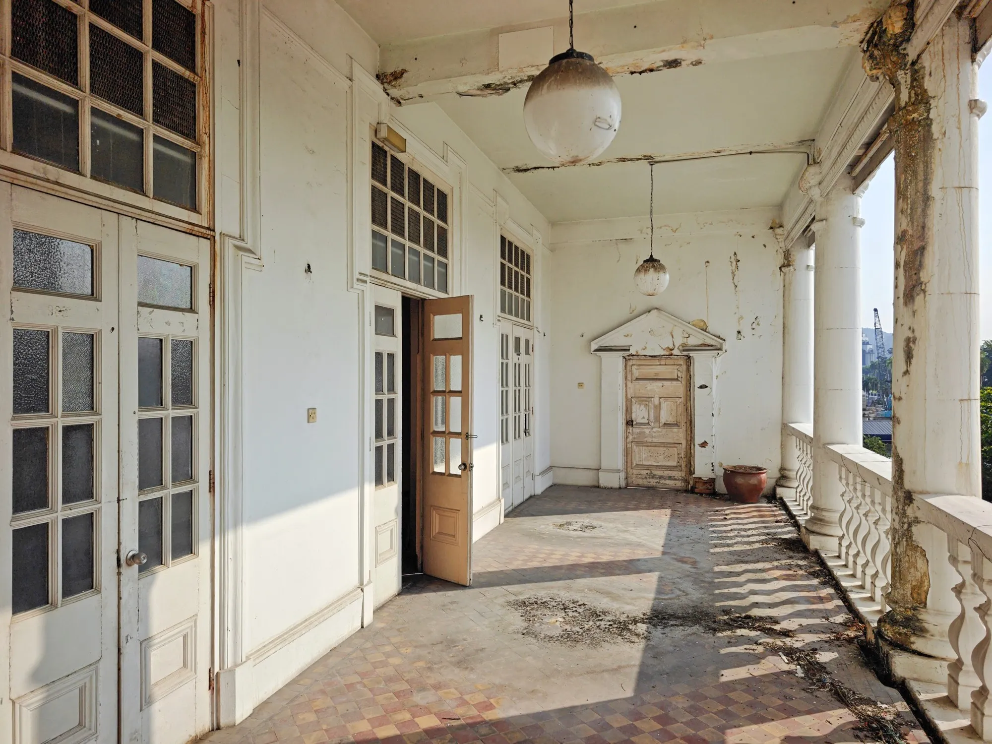 Long white colonnaded loggia with tiled floor and hanging lamps at the former Station Hotel