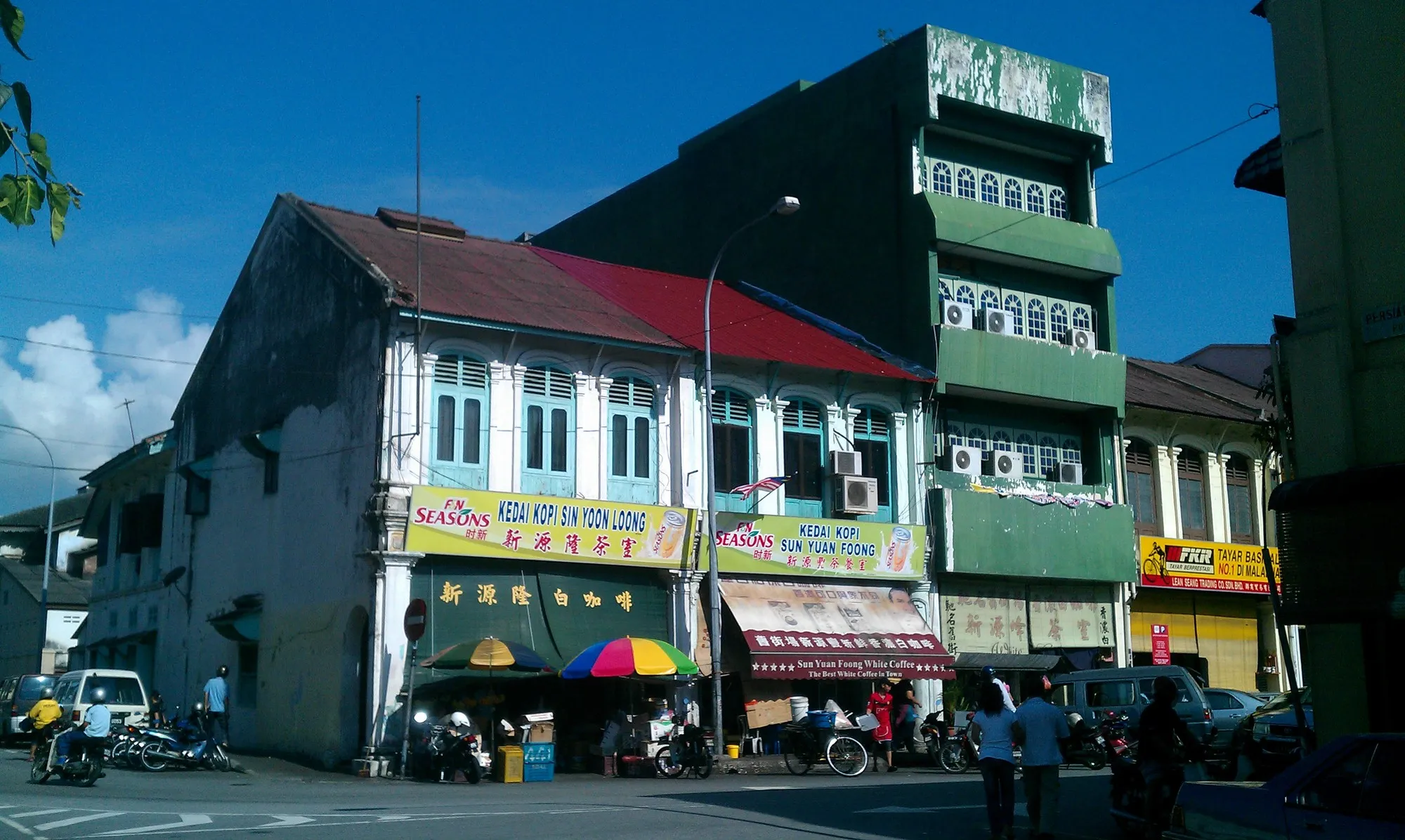 Deretan rumah kedai lama dengan kanopi kedai kopi di Jalan Bandar Timah, Bandar Lama Ipoh, di bawah langit biru