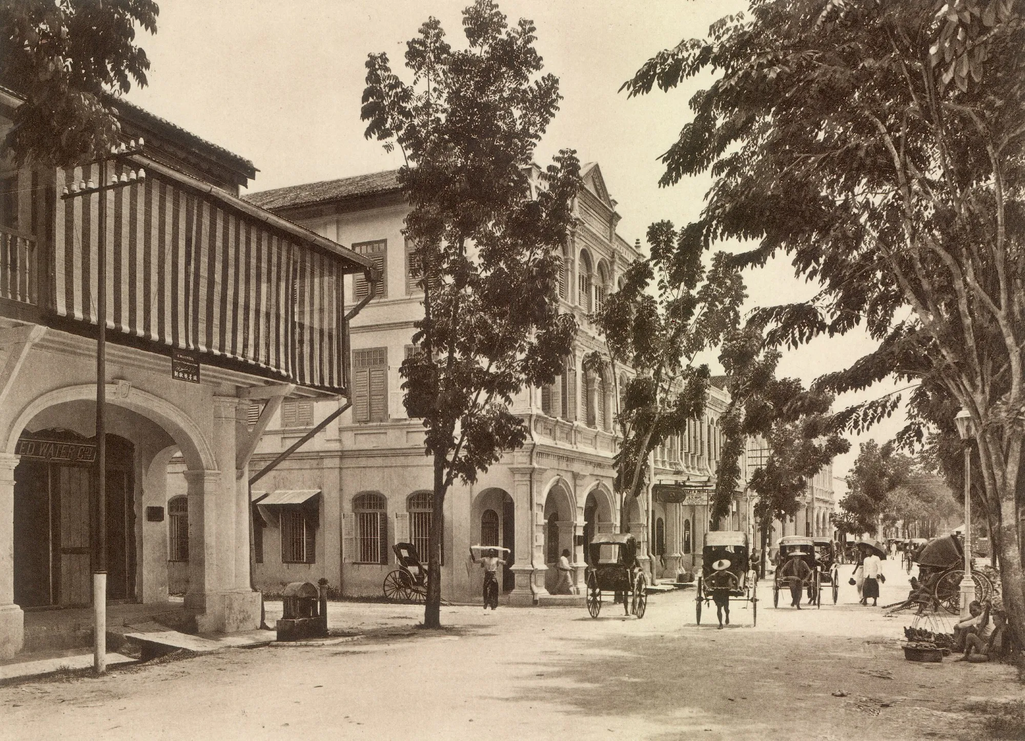 约1910年怡保 Station Road 的棕褐色旧照，有店屋骑楼、树木和人力车