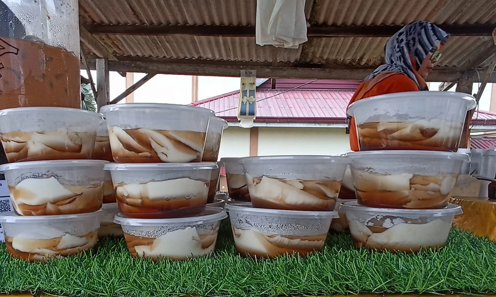 Stacked bowls of white soybean pudding in brown syrup at a stall
